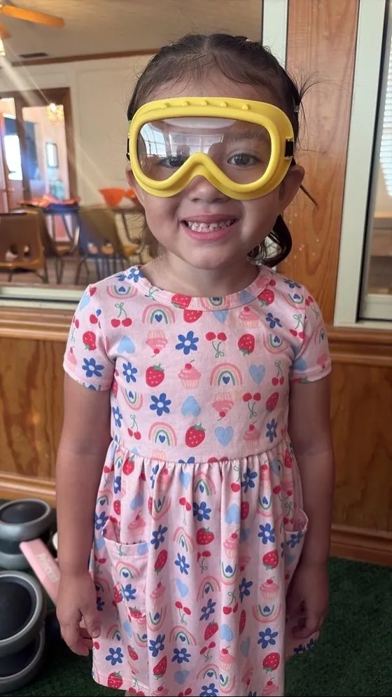 A child wearing play goggles and smiling at Bright Haven