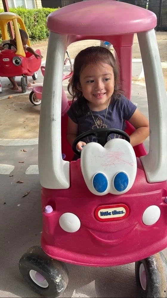 A child playing in a toy car outside at Bright Haven